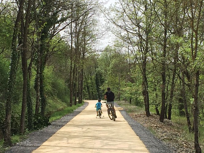 Un adulte et un enfant font du vélo sur une voie verte